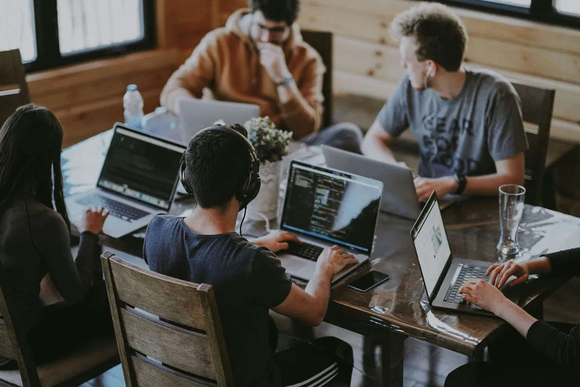 Team van developers dat samenwerkt rond laptops
